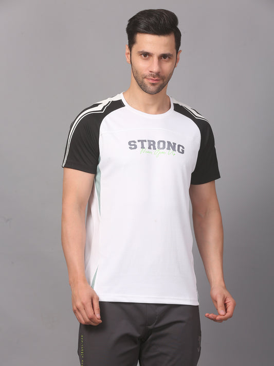 A man wearing a white round neck T-shirt with black sleeves and text on the chest, paired with dark pants.